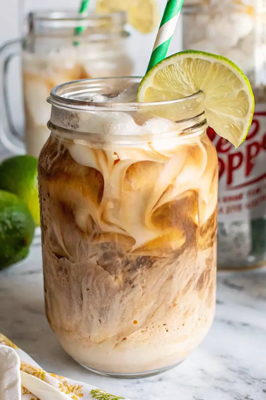 adding coconut syrup to a tall glass of iced Dr Pepper