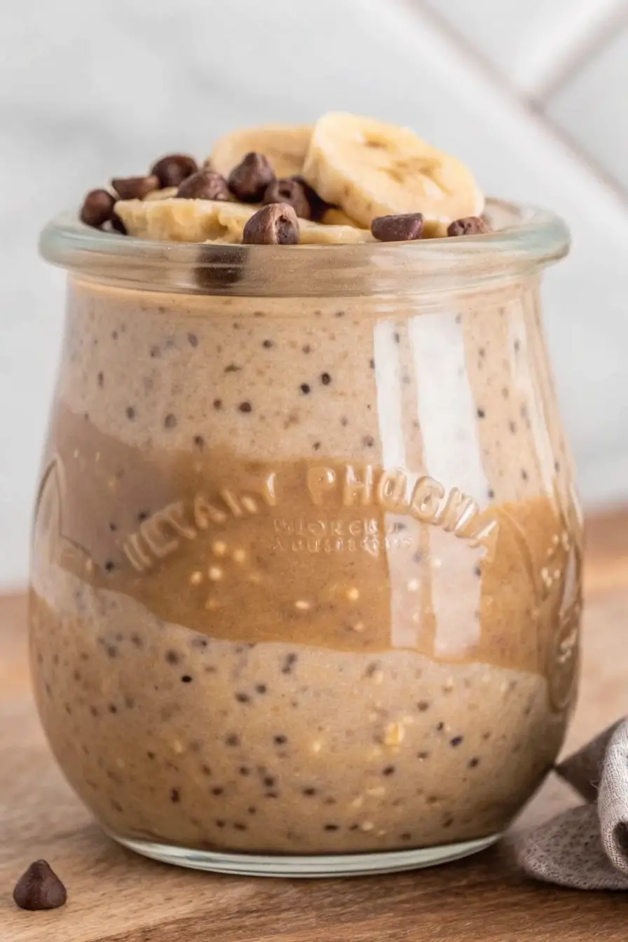 High Protein Overnight Oats layered with peanut butter, chia seeds, and berry jam in a glass jar